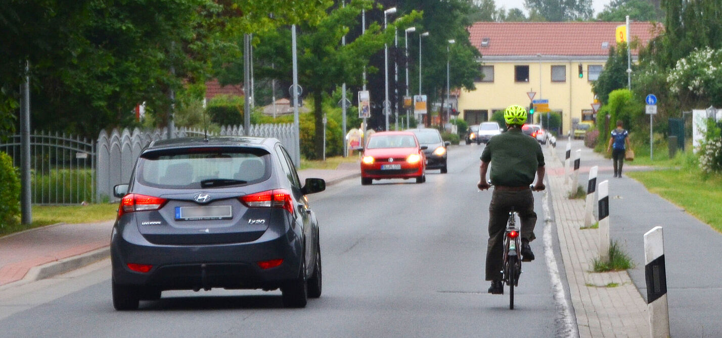 Radfahrer wird überholt Ein Auto überholt einen Radfahrer und hält sich dabei weit entfernd von ihm