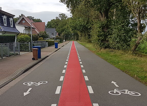 Fahrradstraße innerorts, asphaltiert mit rotem Mittelstreifen und Fahrrad-Piktogrammen