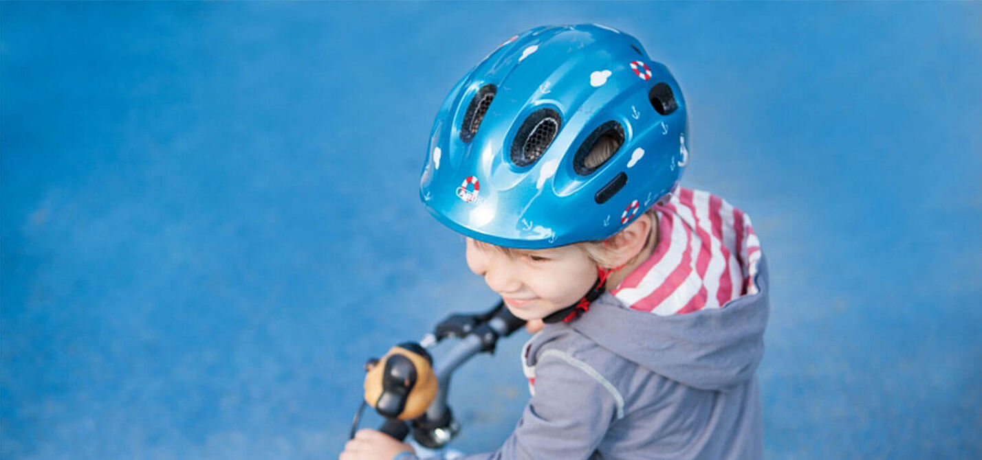 Kind mit Helm und Laufrad