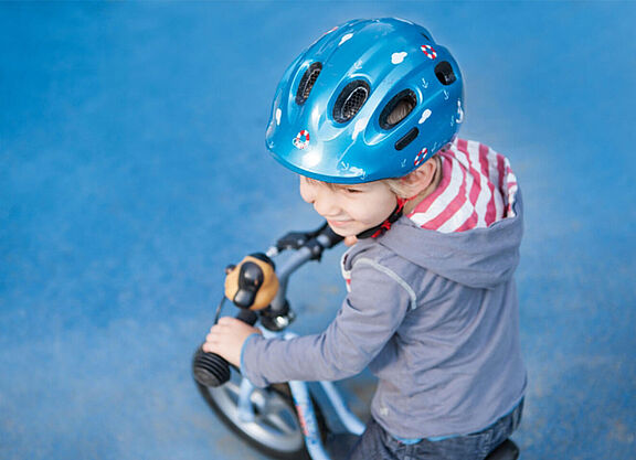 Kind mit Helm und Laufrad