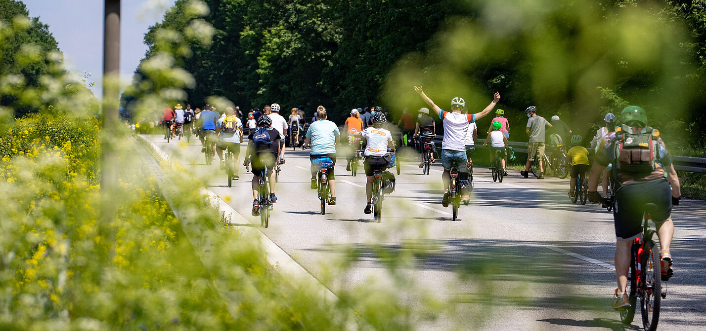 Radfahrer bei Sternfahrt neben Schild zu Geschwindigkeitsbegrenzung 100h/km